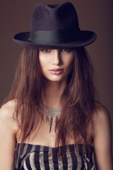 Woman with open lips in black hat on dark background