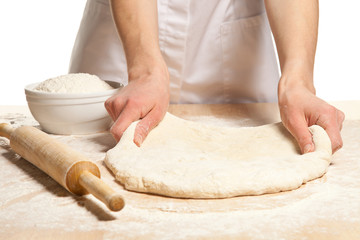 Hands stretching dough on wooden table