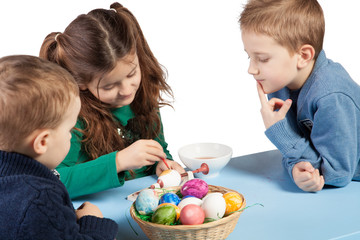 Three children painting Easter eggs