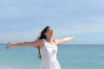 Fototapeta na wymiar Happy beautiful girl with her arms raised on the beach