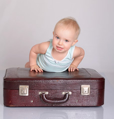 baby girl playing with suitcase on grey background