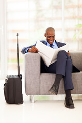 african businessman reading newspaper in airport vip lounge