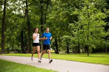 Tuinposter Jogging together - young couple running © Martinan