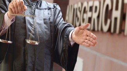 Rechtsanwalt mit Waage vor Gerichtsgebäude