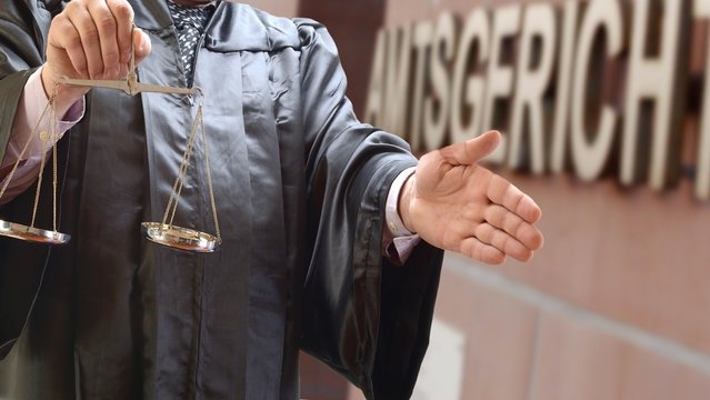 Rechtsanwalt mit Waage vor Gerichtsgeb&auml;ude