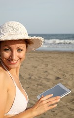 Fototapeta premium woman at the beach with tablet-pc