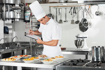 Chef With Clipboard Going Through Cooking Checklist