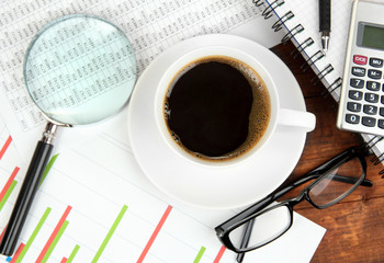 Cup of coffee on worktable covered with documents close up