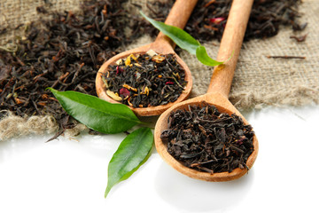 Dry tea with green leaves in wooden spoons, isolated on white