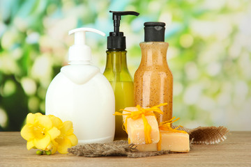 Liquid and hand-made soaps on wooden table, on green background