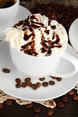 Cup of whipped cream coffee on wooden table close up