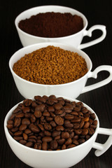 Different types of coffee in three cups on wooden table