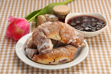Taste croissants on plate and jam on tablecloth.