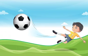 Fotobehang Een jongen die voetbal speelt in de heuvels © GraphicsRF