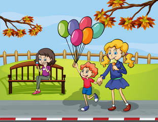 Two girls with a kid holding a balloon in the park