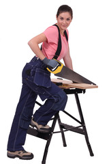 Woman sawing plank of wood