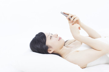 ベッドでスマートフォンを使う女性