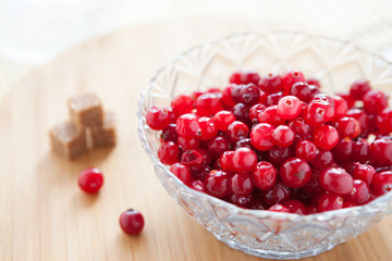 ripe cranberries in a glass bowl and refined sugar