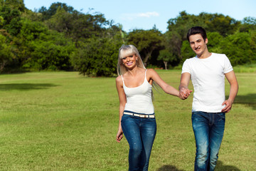 Young couple hopping together in park.