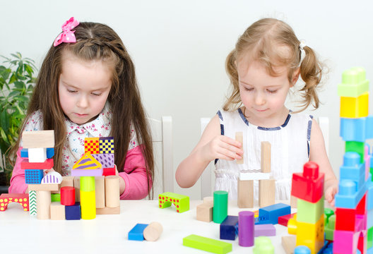 Two little girl playing with building blocks