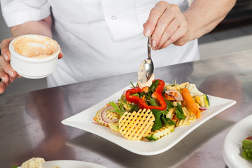 Female Chef Garnishing Dish At Counter