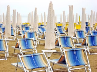 sun beds and umbrellas closed in a deserted sandy beach