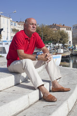 70's man meditating on a stairs outside in the sun