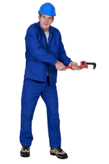 Tradesman trying to pull an object using a pipe wrench