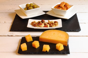 Aperitivo de queso, aceitunas, galletas saladas y frutos secos