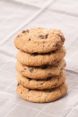 Stacked chocolate chip cookies on brown napkin.