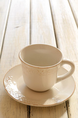 Fototapeta na wymiar Pusty kubek kawy z kremowym kolorze na drewnianym stole