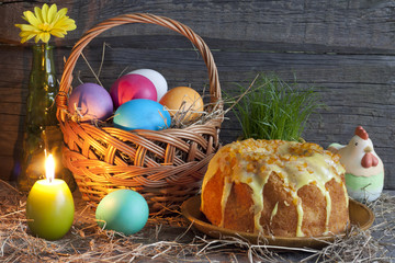 Easter eggs in the basket and cake on vintage wooden table