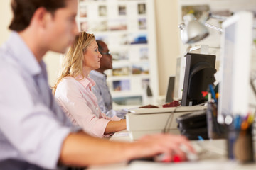 Workers At Desks In Busy Creative Office