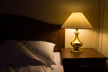 Brass lamp scatter a dim yellowish light over a bed and side table