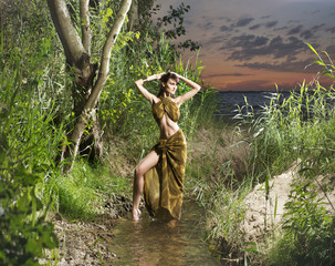 A young and beautiful savage girl posing in the jungle