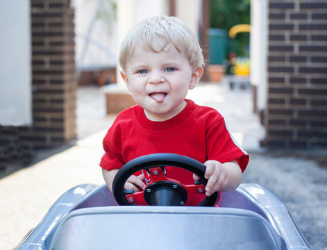 Little todder boy playing with big toy car