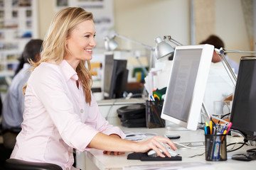 Woman Working At Desk In Busy Creative Office