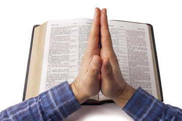 Praying hands over open bible