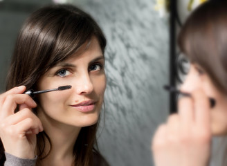 brunette girl making up her blue eyes