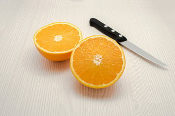 Halved an orange and a knife on the table