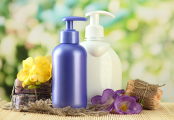 Liquid and hand-made soaps on wooden table, on green background