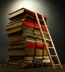 Old books and wooden ladder, on grey background