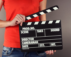 Movie production clapper board in hands on grey background