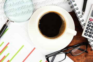 Cup of coffee on worktable covered with documents close up
