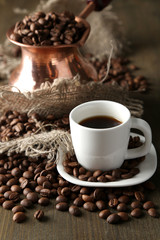 Cup of coffee and pot on wooden background