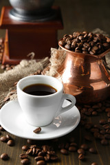 Cup of coffee, pot and grinder on wooden background