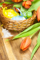 Obraz na płótnie Canvas Easter eggs in basket and orange tulip on wooden background