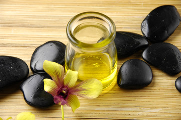 Fototapeta na wymiar Massage oil and black stones with orchid