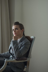 Thoughtful business woman sitting in chair in hotel room