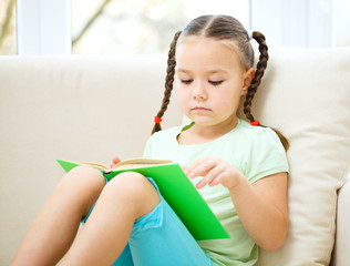 Little girl reads a book